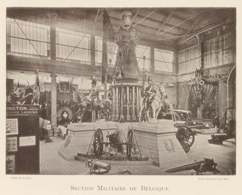 Exhibition of Belgian weapons during the World Exhibition in Antwerp, Section Militaire de Belgique, page, photomechanical print, photographer: Th. Lantin, Antwerp, clichémaker: Joseph Maes, 1894, paper, collotype, photogravure, height 160 mm x width 220 mm, weapons, world fair, world exhibition, exhibition, show, A large indoor exhibition space with tall windows and a high roof showing exposed beams and metal supports contains multiple displays of military equipment including cannons, ammunition, and wheeled artillery pieces arranged on wooden flooring and raised stone-like platforms; a central tall cylindrical structure decorated with vertical elements and topped with ornamental radial pieces stands prominently, flanked by two mounted figures in uniform on horses wearing decorative bridles and saddles; flags and banners hang around the perimeter and decorative fan-shaped arrangements and ladders are visible against the walls, while various smaller objects and framed panels are positi...