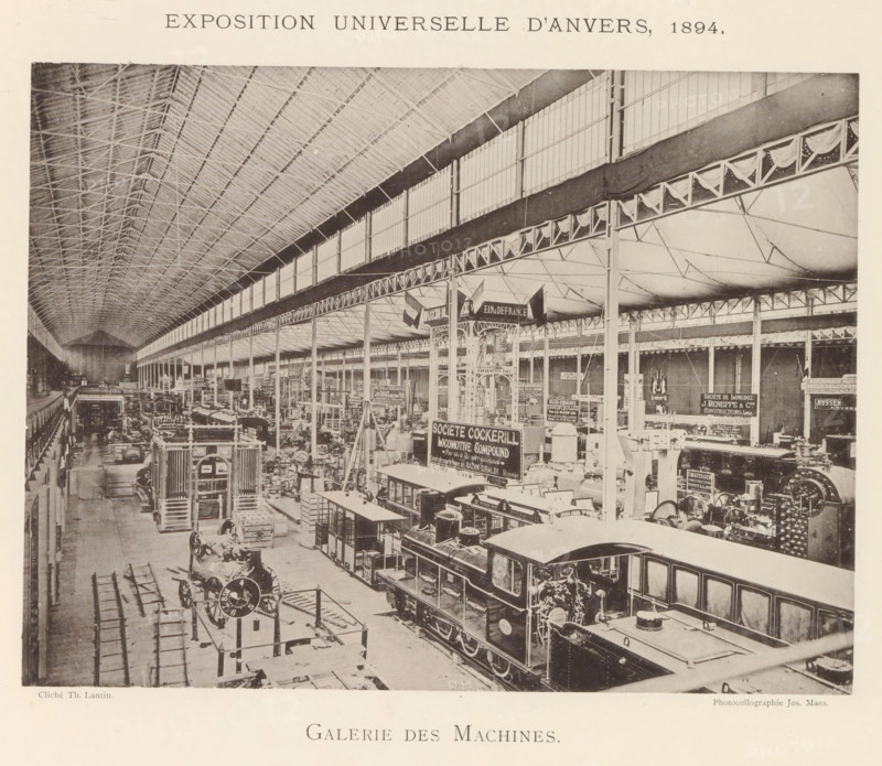 Galerie des machines, Interior of the machine hall during the World Exhibition in Antwerp, page, photomechanical print, photographer: Th. Lantin, Antwerp, cliché maker: Joseph Maes, 1894, paper, collotype, photogravure, height 163 mm x width 218 mm, interior, representation of a building, world fair, world exhibition, exhibition, show, machines, parts of machines, tools and appliances, A wide interior view of a large industrial exhibition hall with a high arched roof supported by a grid of metal trusses and rows of tall vertical columns, an upper gallery with large paneled windows running along the length of the space, and decorative draped fabric along a horizontal beam; the floor area is filled with rows of large machines and locomotives positioned on tracks, various mechanical components, display stands, and scaffolding, with signs and banners mounted above some exhibits; a foreground locomotive with a visible cab and boiler sits on rails, other machinery and engine parts occupy the...