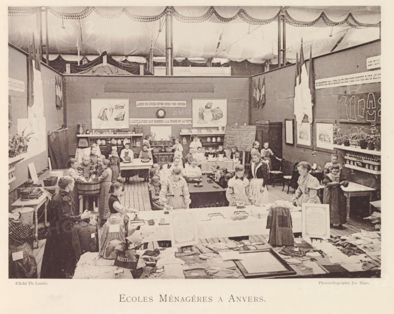 Girls and women in a studio of the domestic science school during the world exhibition in Antwerp, Ecoles Ménagères a Anvers, page, photomechanical print, photographer: Th. Lantin, Antwerp, cliché maker: Joseph Maes, 1894, paper, collotype, light printing, height 161 mm x width 220 mm, scholastic education, tuition, household management, housewife at work, world fair, world exhibition, exhibition, show, A large indoor room under a draped ceiling is filled with children and adults standing and seated at tables and around workstations, many wearing aprons and simple dresses; tables display folded garments, cloth pieces, and small objects, while shelves and a stove line the back wall holding dishes and pots. The back partition walls are decorated with framed pictures and posters, hanging flags, and a chalkboard leaning against a cabinet, with potted plants on a side shelf. Several groups of children are clustered around tubs and tables where they appear to be engaged with the objects on t...