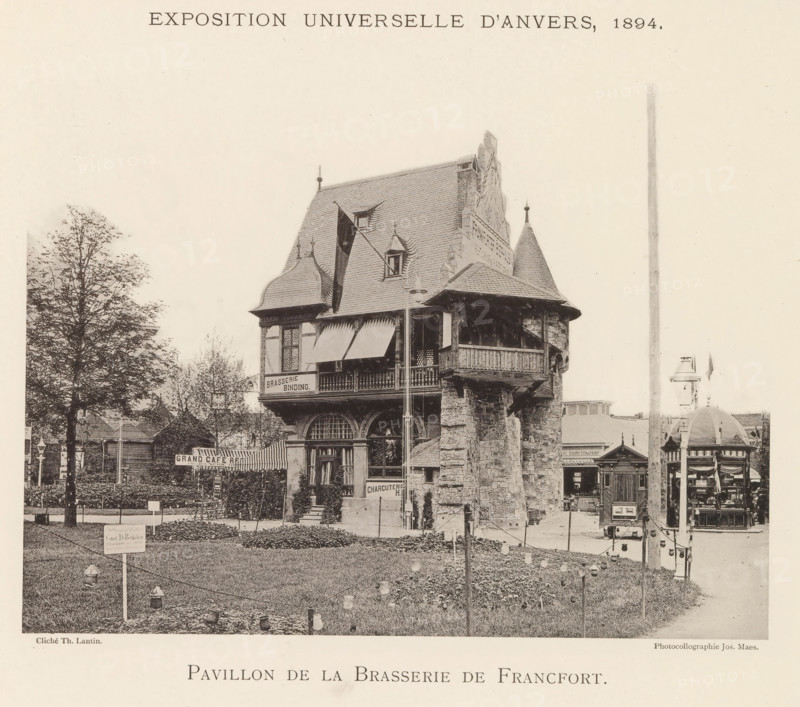 Pavilion of the Frankfurter Bierhaus at the World Exhibition in Antwerp, Pavillon de la brasserie de Francfort, page, photomechanical print, photographer: Th. Lantin, Antwerp, printer (person): Joseph Maes, 1894, printer (person), paper, collotype, photogravure, height 163 mm x width 215 mm, restaurant, façade (of house or building), world fair, world exhibition, A sepia-toned photograph of a multi-story stone and timber pavilion with steep shingled roofs, decorative gables, and a corner turret featuring a conical roof and a balcony supported by rough stone piers; a flag hangs from a pole attached to the upper story and awnings shade the balcony and windows; a grassy foreground with low hedges, stringed lights on posts, and a small signpost leads toward the building, while trees stand to the left and additional smaller structures and kiosks appear to the right and rear.