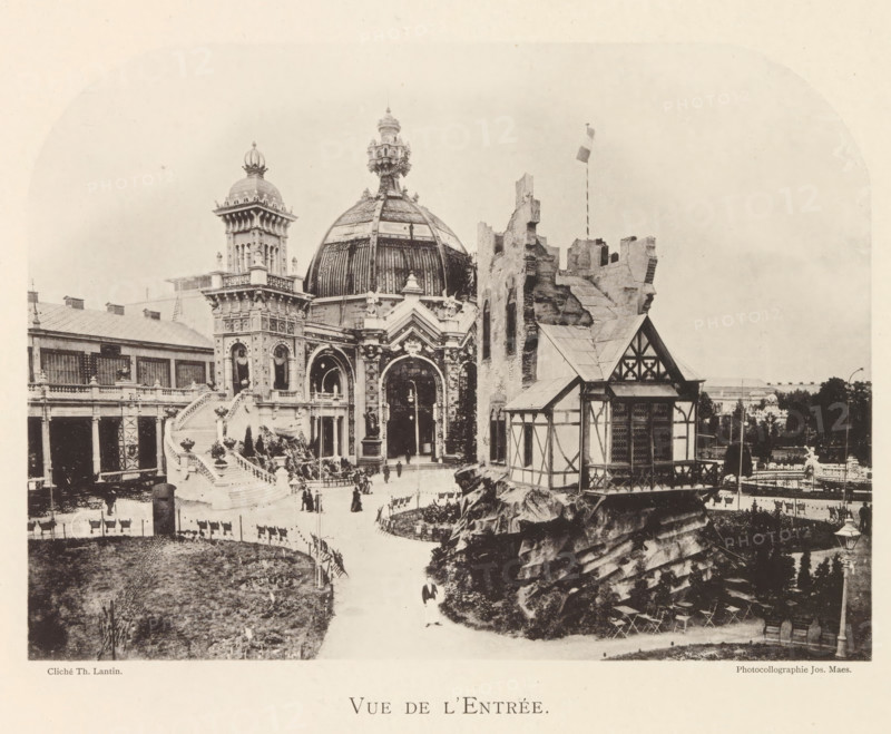 View of the entrance portal of the world exhibition in Antwerp, Vue de l'entrée, page, photomechanical print, photographer: Th. Lantin, Antwerp, printer (person): Joseph Maes, 1894, Th. Lantin, Joseph Maes, photographer, printer (person), paper, collotype, photoprint, height 159 mm x width 219 mm, facade (of house or building), gate, entrance, world fair, world exhibition, A sepia-toned photograph of an ornate entrance featuring a large domed pavilion with decorative arches and sculptural details, flanked by a tall tower with a crowned dome and a partially ruined stone structure with a flagpole. In front of the domed building a broad staircase with balustrades leads down to a courtyard where small groups of people are walking and standing. To the right a timber-framed building sits atop a rocky outcrop with visible beams and patterned window shutters. In the foreground a curved path runs past grassy areas and fenced beds, and a row of outdoor chairs and a lamppost are visible near the ...