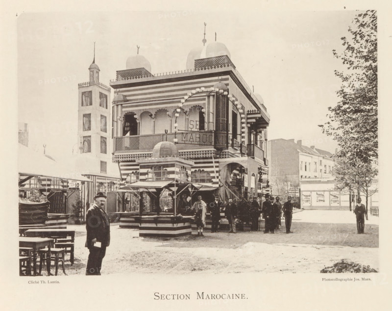 Section Marocaine, Exterior of the Moroccan pavilion at the World Exhibition in Antwerp, page, photomechanical print, photographer: Th. Lantin, Antwerp, printer (person): Joseph Maes, 1894, printer (person), paper, collotype, photogravure, height 158 mm x width 219 mm, façade (of house or building), world fair, world exhibition, A striped two-story pavilion with domed turrets and decorative arches stands near a tall tower with lattice-covered windows, surrounded by market stalls and wooden benches; several men in period clothing stand and pose in front of the pavilion while another man in a hat stands closer to the foreground holding an object, and trees and neighboring buildings are visible along the right side of the scene.