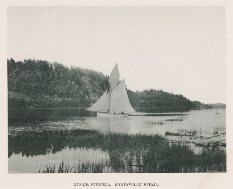 View of a sailing boat in the water, Otsais niemelä. Sortavalan pitäjä, page, photomechanical print, photographer: Impi Backman, cliché maker: anonymous, printer (person): Weilin & Göös, c. 1888 - c. 1893, printer (person), paper, autotypie, height 158 mm x width 208 mm, sailing-ship, sailing-boat, trees, landscapes with waters, waterscapes, seascapes (in the temperate zone), Karelia, A grainy black-and-white scene of a calm body of water bordered by reeds in the foreground and a tree-covered rocky shoreline in the background, with a sailboat on the water featuring a large triangular sail and a smaller secondary sail and several small figures aboard, and a pale sky filling the upper portion of the image.