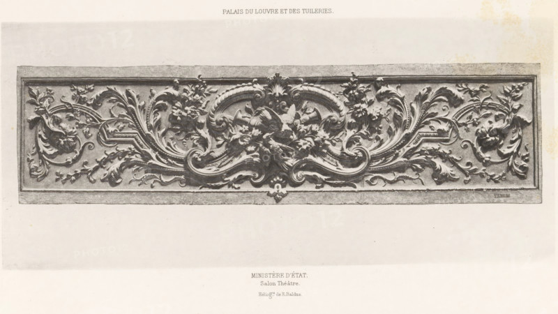 Ministère d'état. Salon théâtre, Ornament with arabesques of a salon (presumably) in the Palais des Tuileries in Paris, Palais du Louvre et des Tuileries, page, photomechanical print, number: 'Int. 29', maker: Édouard Denis Baldus, Paris, c. 1865 - in or before 1870, Édouard Denis Baldus, paper, photoaquatint, height 121 mm x width 271 mm, ornaments, art, ornament, arabesque, A rectangular carved panel with an ornate central relief featuring symmetrical flowing acanthus leaves, curling scrolls, and clusters of flowers, rendered in a high-contrast grayscale; the design includes a prominent central motif with layered curved ribs and leafy forms radiating outward into mirrored swirling foliage and floral sprays, all set within a raised border and framed by a plain rectangular edge, photographed against a light background with visible paper texture.