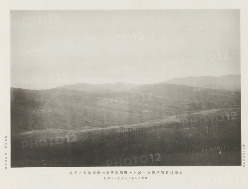 Attack of the first artillery regiment, S. of Shihtsuytse, at Port Arthur, page, photomechanical print, inscription: 'The fall of Port Arthur.', photographer: Ordnance Survey, Manchuria, cliché maker: Kazumasa Ogawa, Japan, 1894-11-21, paper, collotype, photoprint, height 190 mm x width 278 mm, army 'en route', A grayscale photograph showing a wide, gently rolling landscape with layered hills fading into the distance under a pale sky, the foreground appearing darker with subtle textures and a faint winding path or depression, midground hills with soft gradients of shadow and light, and distant ridgelines that are lighter and more diffused.