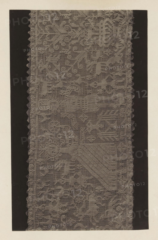 German scene in lace from the collection of Antonin Terme, photograph, page, Liège, c. 1880 - in or before 1885, photographer, paper, platinum process, height 138 mm x width 224 mm, lace, art collection, art gallery, A vertical strip of patterned lace fabric runs down the center, showing a detailed open weave with repeating floral and geometric motifs and scalloped edges on both sides; the lace appears in a muted gray tone against darker vertical bands that frame it, and a light neutral background surrounds the framed area.