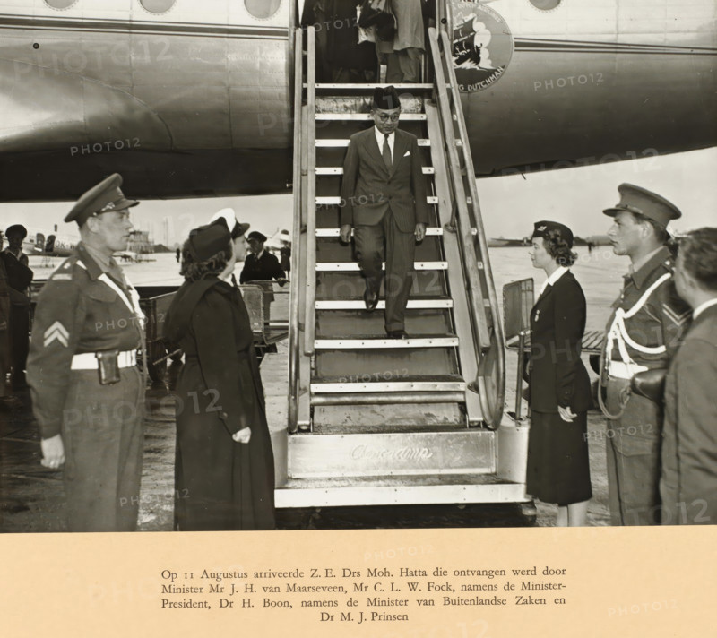 On August 11, HIS Dr. Moh. Hatta arrived and was received by Minister Mr. JH. van Maarseveen, Mr. CLW. Fock, on behalf of the Prime Minister, Dr. H. Boon, on behalf of the Minister of Foreign Affairs, and Dr. MJ. Prinsen, photograph, Arrival of Prime Minister Mohammed Hatta at Schiphol on August 11. Hatta walks down the stairs of the KLM aircraft. Photo in the photo album with 37 photos of the round table conference held between August 23 and November 2 in The Hague in 1949 between representatives of the Netherlands, the Republic of Indonesia, and the Federal Consultative Body. The copy presented to Prime Minister Willem Drees., photographer: Government Information Service, Schiphol, 1949-08-11, paper, gelatin silver print, gelatin silver print on album page, height 170 mm x width 227 mm, height 292 mm x width 400 mm, Person, Mohammad Hatta, Johannes Henricus van Maarseveen, Round Table Conference (1949), Period, 1949-08-23 - 1949-11-02, A man wearing a dark suit, tie, pocket square, g...