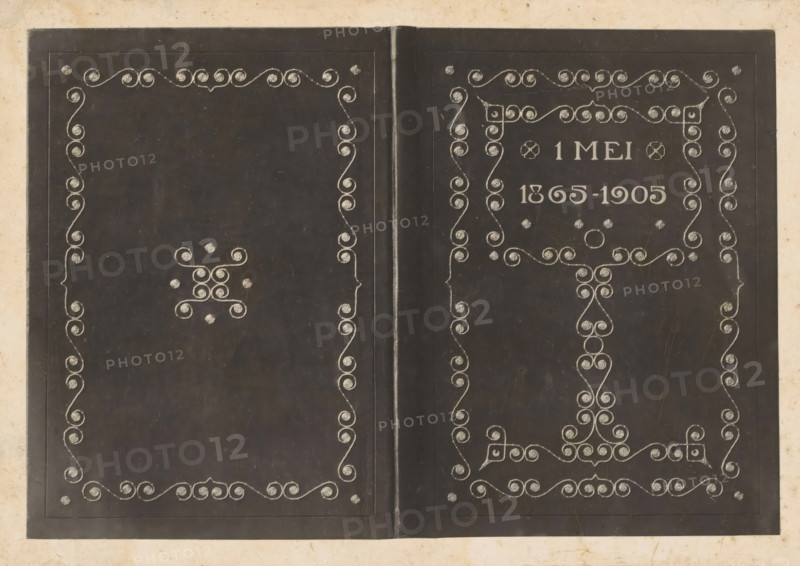 Band of the album 1865-1905, photograph, name: 'RWP de Vries', annotation: 'let this be made into a cliché, R...', collector's mark: 'R:MVS.', after design by Reinier Willem Petrus de Vries (1874-1953), in or after 1905 - 1986, Reinier Willem Petrus de Vries (1874-1953), photographer, after design by, paper, pasteboard, daylight collodion silver print, height 138 mm x width 199 mm, A dark, open book with two pages visible, each page framed by a thin rectangular border and decorated with symmetrical, ornate swirled line patterns in a lighter color, including spirals arranged along the inner and outer margins and clustered decorative motifs near the centers and corners; a vertical seam runs down the middle where the pages meet, and the background surrounding the book is a lighter, aged paper tone with subtle stains and speckles.