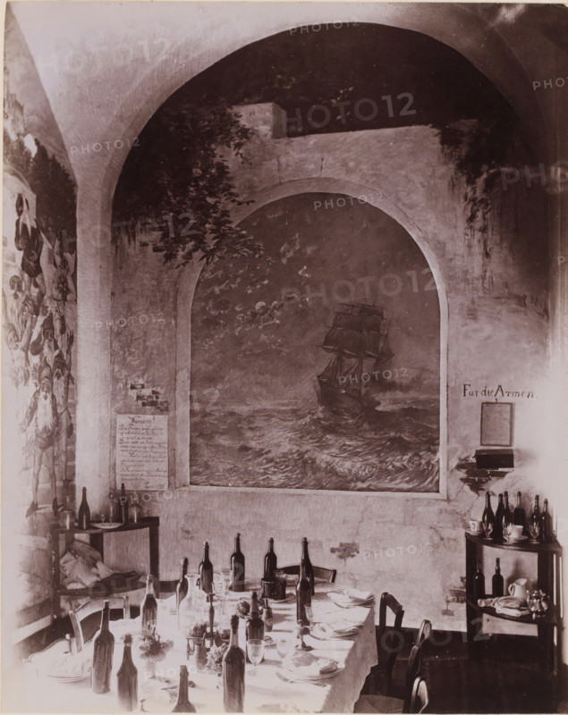 Interior of the dining room of Hotel Pagano in Capri, Italy, Hotel Pagano, Capri, photograph, number: '6126', photographer: attributed to Giorgio Sommer, 1857 - 1915, Attributed to, pasteboard, paper, albumen print, height 250 mm x width 445 mm, hotel, hostelry, inn, Isola di, A dining scene under a high arched ceiling with a large painted mural of a sailing ship set into a recessed arch on the wall, flanked by painted foliage and wall murals, a long table covered with a cloth arranged with empty and partially filled bottles, glassware, plates, folded napkins, and small floral arrangements, chairs pushed around the table, shelving and small tables at the sides holding additional bottles, cups, pitchers, and stacked items, and visible worn plaster and brickwork on the walls.