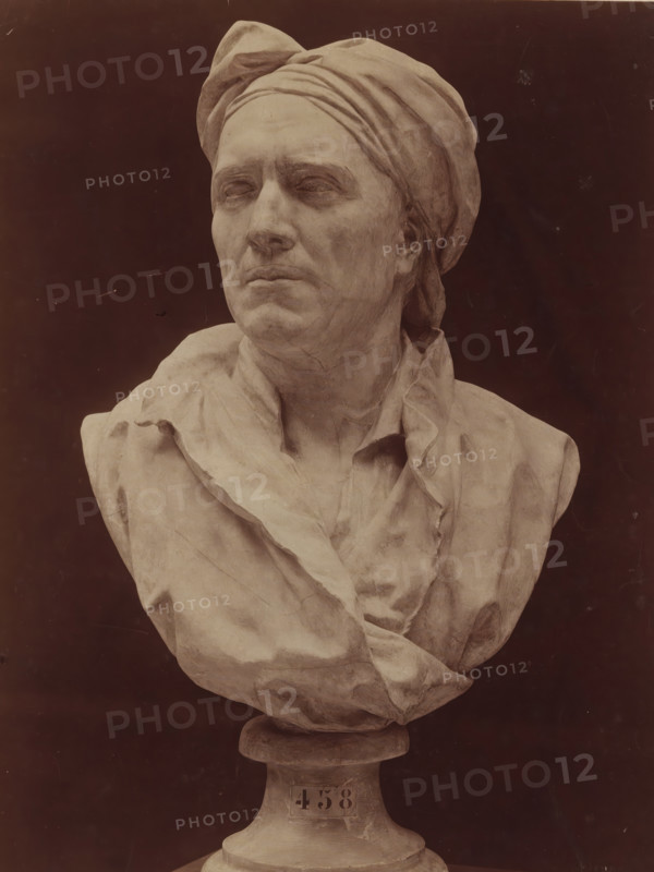 Bust of Nicolas Coustou by G. Coustou, G. Coustou Bust of Nicolas Coustou. Château de Versailles, photograph, number: 'T 458', inscription: 'Guillaume Coustou.', collector's mark: 'Rijks-SCHOOL FOR DRAWING TEACHERS AMSTERDAM', name: 'A. GIRAUDON EDITEUR 15. R. BONAPARTE PARIS', photographer: Adolphe Giraudon, publisher: Adolphe Giraudon, Paris, c. 1875 - c. 1900, Adolphe Giraudon, photographer, publisher, paper, pasteboard, albumen print, height 261 mm x width 203 mm, sculpture, historical persons ((full) bust portrait), A monochrome bust of a person wearing a wrapped headscarf and draped garment is shown against a dark background, the face turned slightly to one side with closed or blank eyes and a neutral mouth, detailed sculpted facial features and textured folds in the cloth visible, the bust rests on a rounded pedestal.