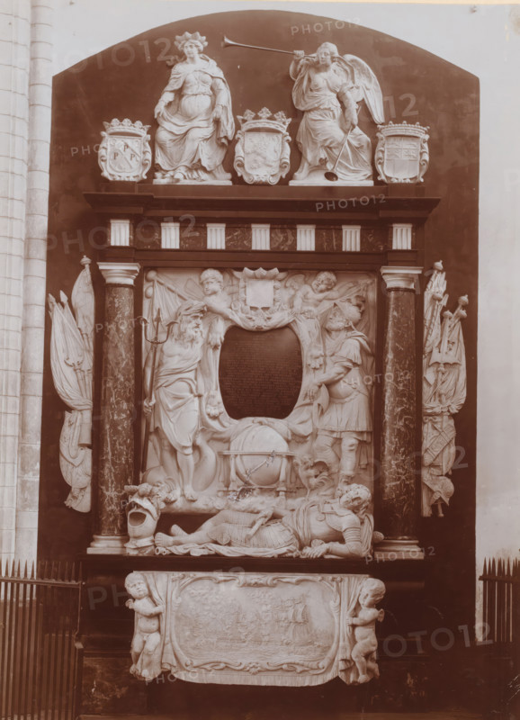 Tomb monument of Cornelis de Witt in the Grote or Sint-Laurenskerk in Rotterdam, photograph, annotation: 'RK St. Laurentius kerk, Grafmonument Witte Corn. de Witt, Aug. 1911, Rotterdam', collector's mark: 'R.MUS.', annotation: 'Lodewijk XIV, 1640-1715', Grote or Sint-Laurenskerk (Rotterdam), 1911, photographer, Rotterdam, Attributed to, paper, pasteboard, daylight collodion silver print, height 219 mm x width 156 mm, Person, Cornelis de Witt, interior of church, grave-building, monumental tomb, A sculptural wall monument set within a dark recessed arch features a pair of seated female figures atop a ledge, one holding a long trumpet and the other with draped robes, flanked by decorative cartouches; below them are columns with marbleized shafts supporting a carved relief scene that includes standing male figures in classical attire, reclining armored figures, cherubic figures, an ornamental shield-shaped panel, and a large spherical object entwined with drapery, with carved draped cloth...