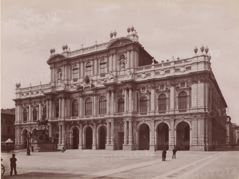 Piazza Carlo Alberto. - Facciata moderna del Palazzo Carignano, View of the Piazza Carlo Alberto and Palazzo Carignano in Turin, Italy, Torino, photograph, number: '3698.', number: '17', photographer: Giacomo Brogi (possibly), Turin, publisher: attributed to Edizioni Brogi, Florence, 1864 - 1881, Tuscany, Piedmont, Attributed to, pasteboard, paper, albumen print, height 317 mm x width 445 mm, square, circus, palace, Palazzo Carignano, Piazza Carlo Alberto, A large ornate stone building with multiple levels of arched windows and tall columns occupies the scene, featuring decorative balustrades, sculpted figures set into niches, and ornamental urns along the roofline; a broad ground-level arcade with rounded arches runs across the facade; a mounted equestrian statue on a raised pedestal stands near the building, surrounded by smaller sculptural elements; a few people in period clothing are scattered across the open paved square in front of the building, and a street lamp is visible near ...