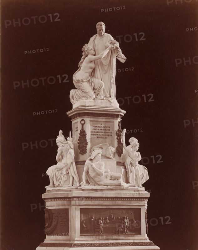 Monument to Camillo Cavour on the Piazza Carlo Emanuele II in Turin, Italy, Piazza Carlo Emanuele II. - Monumento a Camillo Cavour, Giovanni Dupré, Torino, photograph, number: '3673. bis', photographer: attributed to Giacomo Brogi, Turin, publisher: attributed to Edizioni Brogi, Florence, after sculpture by Giovanni Dupré, 1873 - 1881, after sculpture by, Tuscany, Piedmont, Attributed to, pasteboard, paper, albumen print, height 445 mm x width 318 mm, Person, Camillo Benzo Duke of Cavour, piece of sculpture, reproduction of a piece of sculpture, historical persons, monument, statue, Piemonte, Piazza Carlo Emanuele Secondo, A multi-tiered marble monument set against a dark background with a central standing male figure draped in robes looking downward while a partially draped female figure kneels beside him reaching upward toward his hands; below them a pedestal adorned with sculpted reliefs and decorative wreath elements, flanked by seated and reclining figures in classical drapery inc...