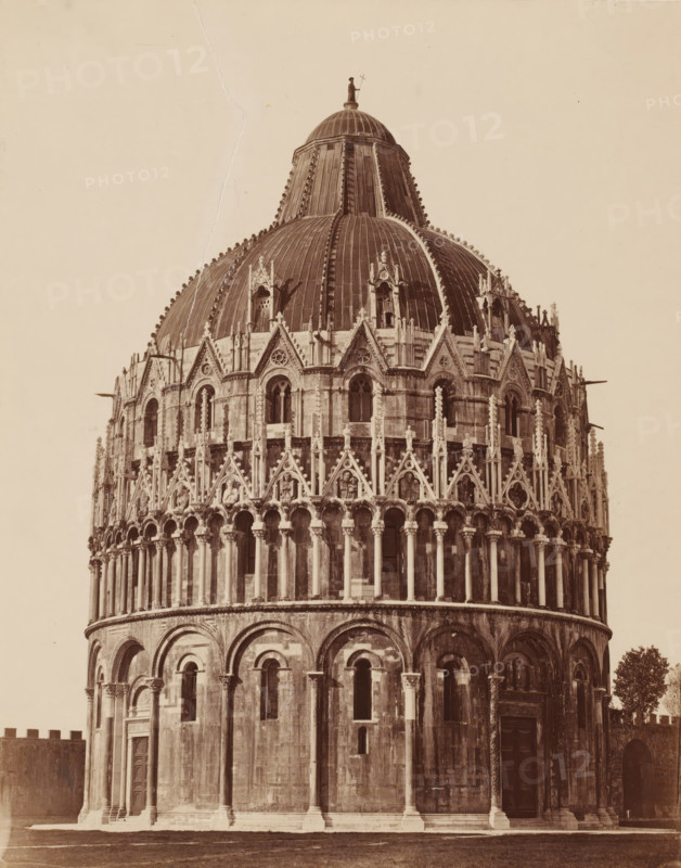 Il Battistero, Exterior of the Baptistery in Pisa, Italy, Pisa, photograph, inscription: 'Pisa', inscription: 'P', number: '3363.', collector's mark: 'RICH SCHOOL FOR ART HANDBOOK, GROUP', inscription: 'RSK N 1', inscription: 'I 23', 1851 - 1900, photographer, Tuscany, pasteboard, paper, albumen print, albumendruk, height 479 mm x width 320 mm, baptism, christening ceremony, the first of the seven sacraments, church (exterior), Baptistery (Pisa), A sepia-toned photograph of a domed stone building showing the upper portion of a circular façade and the large rounded dome above it, with a smaller dome and a statue at the top; the façade displays rows of arched openings, columns, and ornate triangular decorative elements with sculpted figures and detailed stonework; the dome has vertical ribs and small decorative finials along its seams; the lower section shows large rounded arches, recessed windows, and doorways with carved surrounds; a patch of grass is visible at the base and a tree app...