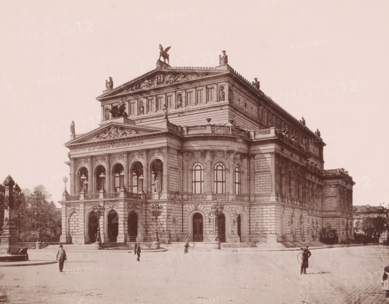Alte Oper', Frankfurt am Main, Germany, photograph, View of the opera house on a square. The building, designed by architect Richard Lucae (1829-1877), was opened in 1880 in the presence of Kaiser Wilhelm I. On March 23, 1944, it was largely destroyed but has been rebuilt., caption: 'Opera. Frankfurt.', in or after 1880 - c. 1895, photographer, pasteboard, paper, albumen print, height 208 mm, width 267 mm x width 330 mm, height 513 mm, A large classical stone building with ornate columns, arches, statues, and sculptural reliefs along its facade and roofline sits on a paved open area, with multiple arched windows and balustraded terraces; decorative lampposts stand near the entrance and small groups of people are walking or standing in the foreground, one person holding a hoop, while trees and additional architectural details appear at the edges of the scene.