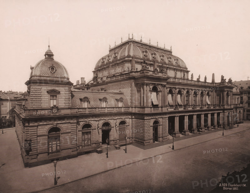 Exhibition building and next to it the 'Concert-Haus', Frankfurt am Main, Germany, photograph, View from the left from an elevated vantage point of the exhibition building and to the left of it the 'Concert-Haus' in Frankfurt am Main, Germany. The building by Frankfurt architects Heinrich Burnitz and Oskar Sommer was opened in 1879., inscription: 'A. 609 Frankfurt a, M., Börse 1892', caption: 'Post office. Frankfurt', 1892, photographer, pasteboard, paper, albumen print, height 212 mm x width 272 mm, height 513 mm x width 330 mm, Hessen, A large ornate stone building occupies the scene with a series of domed and mansard roofs, decorative balustrades, sculpted figures along the roofline, and ornamental cornices; the façade features tall arched windows with awnings, a colonnaded portico with large columns, carved reliefs and decorative keystones above entrances, and a corner pavilion topped by a circular windowed dome; the street in front is paved and largely empty, showing a few cast ir...