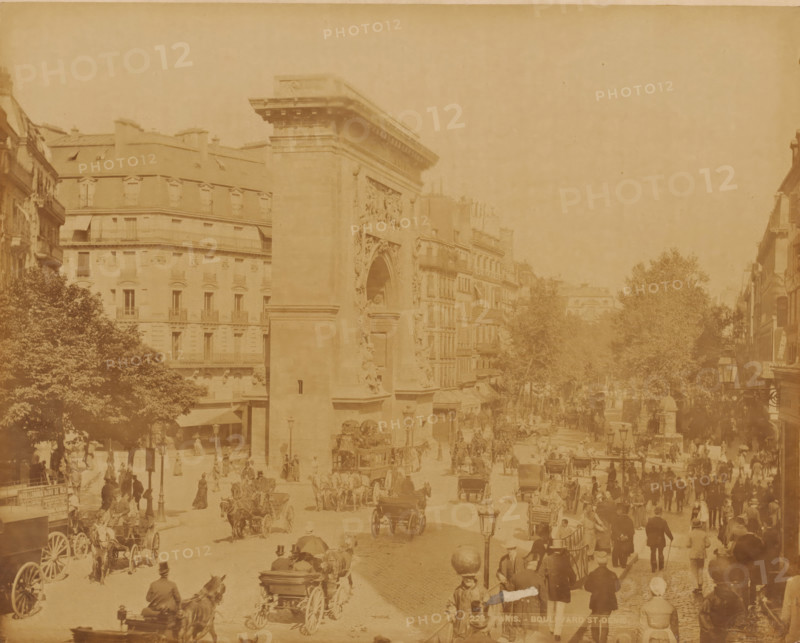 Boulevard St. Denis with the Porte St. Denis, Paris, France, photograph, France., inscription: '228. PARIS. BOULEVARD ST DENIS - LL', check stamp: 'Photography ? Company ?, J.KUHN, PARIS, 220 170174 ? RUE DE RIVOLI', photographer: J. Kuhn, publisher: Léon & Lévy, c. 1865 - c. 1880, pasteboard, paper, albumen print, height 222 mm x width 279 mm, height 304 mm x width 401 mm, A wide street scene with a large stone arch structure at the center left flanked by multi-story buildings with rows of windows and mansard roofs, trees along the street, many horse-drawn carriages and carts on the road, numerous pedestrians on sidewalks and crossing the street wearing period clothing and hats, street lamps and a few awnings over shop entrances visible, and a generally sepia-toned appearance.
