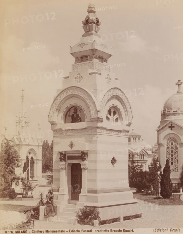 Edicola Fossati, Cimitero Monumentale, Milan, Italy, photograph, Tomb designed by Ernesto Quadri, Cimitero Monumentale cemetery, Italy., caption: '10776. MILANO - Cimitero Monumentale - Edicola Fossati, architetto Ernesto Quadri.', caption: '(EDIZIONI BROGI)', photographer: Edizioni Brogi, Florence, publisher: Giacomo Brogi, c. 1860 - c. 1890, Tuscany, pasteboard, paper, albumen print, height 250 mm x width 195 mm, height 330 mm x width 510 mm, Lombardy, A tall stone mausoleum with layered decorative tiers and carved reliefs dominates the foreground, featuring an arched niche with a painted religious figure and an adjacent circular tracery window, ornate cornices, and sculpted ornamental details; a seated bronze or metal statue of a woman rests on the base steps at the front, near a potted plant and low decorative fence elements; surrounding the mausoleum are trees and landscaped shrubs, a domed building with a cross and patterned facade is visible to the right, and a Gothic-style stru...
