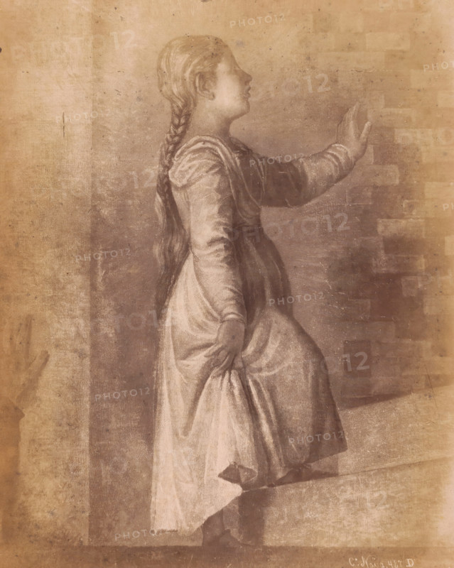 Photo reproduction of detail of painting Presentazione by Titian, Academia Venezia, 487 D in negative, photograph, photographer: Carlo Naya (possibly), c. 1860 - c. 1880, pasteboard, paper, albumen print, height 336 mm x width 267 mm, picture, painting, Venice, Accademia, A sepia-toned drawing of a young woman shown in profile facing right, wearing a long dress with a fitted bodice and full skirt, her hair braided and falling down her back, one arm raised with an open hand touching a wall and the other arm lowered with the hand holding the skirt, visible folds and shading on the fabric, a textured background with brick-like patterns and worn paper marks.