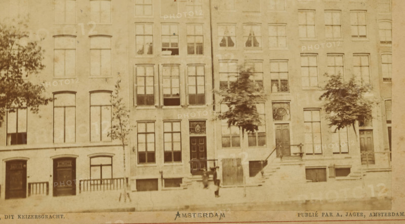 View of a row of houses on the Keizersgracht in Amsterdam, Canal, this Keizersgracht, Amsterdam, photograph, cabinet photograph, collector's mark: 'VOSMAER', publisher: Andries Jager, 1860 - 1890, Andries Jager, photographer, publisher, paper, pasteboard, albumen print, height 100 mm x width 135 mm, height 108 mm x width 168 mm, the usual house or row of houses, street, Keizersgracht, A sepia-toned photograph of a row of narrow multi-story brick buildings with tall rectangular windows and decorative doorways, some windows showing curtains and some open, small trees planted along the sidewalk in front of the buildings, stone steps leading up to several entrances with railings, faint shadows and weathering on the building facades, and a blurred figure standing near the steps.