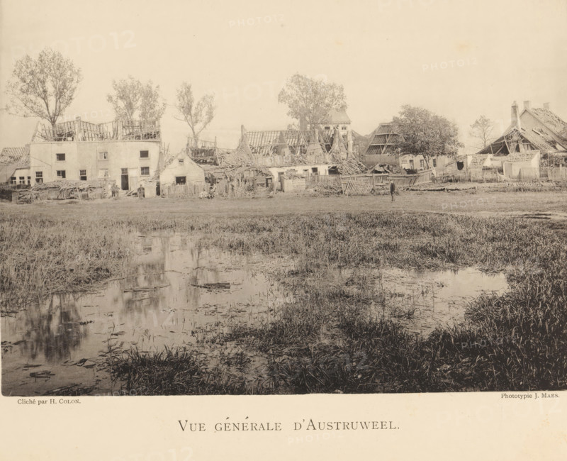 View of Oosterweel with destroyed houses after an explosion of a munitions factory in 1889, Vue générale d'Austruweel, page, photomechanical print, number: '11', photographer: Henri Colon, Oosterweel, cliché maker: anonymous, Belgium, printer (person): J. Maes (possibly), Antwerp, publisher: J. Maes, 1889, Henri Colon, J. Maes, photographer, cliché maker, printer (person), publisher, paper, collotype, photoprint, height 165 mm x width 230 mm, Image on page 11., ruin of a building, architecture, Explosion of a munitions factory in Oosterweel in 1889, A wide, sepia-toned scene shows a row of damaged buildings with exposed wooden roof frames and missing roof sections, interspersed with trees behind and between the structures; in front of the buildings there are scattered fences, piles of debris, and small figures of people standing or sitting near doorways; the foreground is dominated by marshy grassland and shallow water with reflections of the buildings and vegetation, and a lone person...