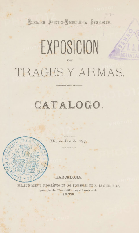 Album fotográfico de la exposition de trajes y armas, celebrada por la Asociación Artístico-Arqueológica Barcelonesa, enero de 1879., book, annotation: 'OCT, 1991', 1878, pasteboard, paper, textile materials, printing, albumen print, albumen printing, height 245 mm x width 179 mm x thickness 25 mm, A worn, aged paper page with large printed headings in bold serif type arranged vertically down the center, decorative rule lines, and ornamental dividers; brownish spotting and foxing marks scattered across the page; a purple triangular stamp partially visible near the top right edge and a circular blue embossed seal with intricate floral and trophy motifs near the lower left; smaller lines of printed text and a faint ornamental flourish toward the middle; overall cream background with uneven discoloration and a narrow blank margin around the edges.