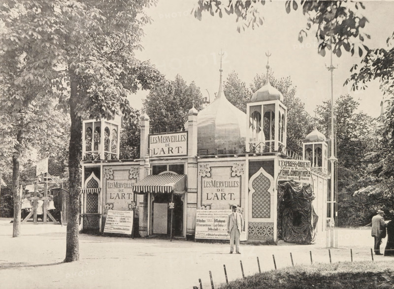 Garden view, Pavilion at the World Exhibition in Antwerp, page, photomechanical print, photographer: Th. Lantin, Antwerp, printer (person): Joseph Maes, 1894, printer (person), paper, collotype, photogravure, height 160 mm x width 218 mm, façade (of house or building), world fair, world exhibition, Wereldtentoonstelling 1894 (Antwerp), A vintage fairground pavilion with ornate domes and turreted towers stands among trees, featuring arched windows, patterned panels, and a striped awning over the entrance; two well-dressed men stand in front and to the side of the building, one facing the camera and the other turned away; a row of low posts lines the foreground edge of a path, and large leafy trees frame the scene on both sides.