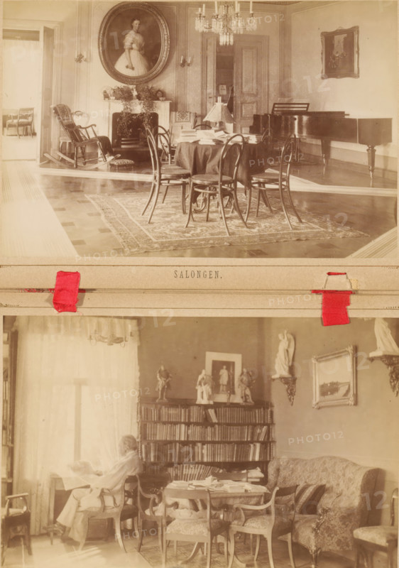 Biblioteket, Interior of the library of the Koivuniemi country house in Helsinki, photograph, page, photographer: Daniel Nyblin, Koivuniemi, c. 1879 - in or before 1884, Helsinki, paper, albumen print, height 100 mm x width 153 mm, study, 'studiolo', library, interior, representation of a building, The image shows two sepia-toned interior photographs stacked vertically; the upper photograph depicts a formal room with a round table covered by a cloth, surrounded by bentwood chairs, a patterned rug beneath, a fireplace with decorative foliage and an oval portrait above it, a chandelier hanging from the ceiling, a rocking chair near an open doorway, and a grand piano along the right wall; the lower photograph shows a cozy room with a person seated in an armchair reading, a bookshelf filled with books and topped with small statuettes, a round table cluttered with papers and surrounded by upholstered chairs, a cushioned sofa with patterned pillows, framed artwork on the walls, and light str...