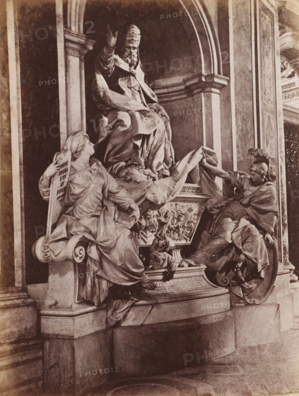 Sculpture of Pope Gregory XIII by Camillo Rusconi St. Peter's Basilica in Vatican City, photograph, page, St. Peter's Basilica, c. 1850 - in or before 1860, photographer, Vatican City, paper, albumen print, height 128 mm x width 97 mm, Person, Gregory XIII, monument, statue, A sepia-toned photograph of a sculptural group set within an arched architectural niche, featuring a seated, robed figure wearing a tall, ornate headdress with one arm raised, flanked by two reclining draped figures on either side; the left figure leans against a scroll-like support and looks upward while holding a tablet, the right figure reaches across toward the seated figure while resting on a rounded shield base; richly textured drapery, carved relief panels, and decorative molding surround the figures, and the scene rests on a stepped stone plinth with visible veining and a patterned floor in front.
