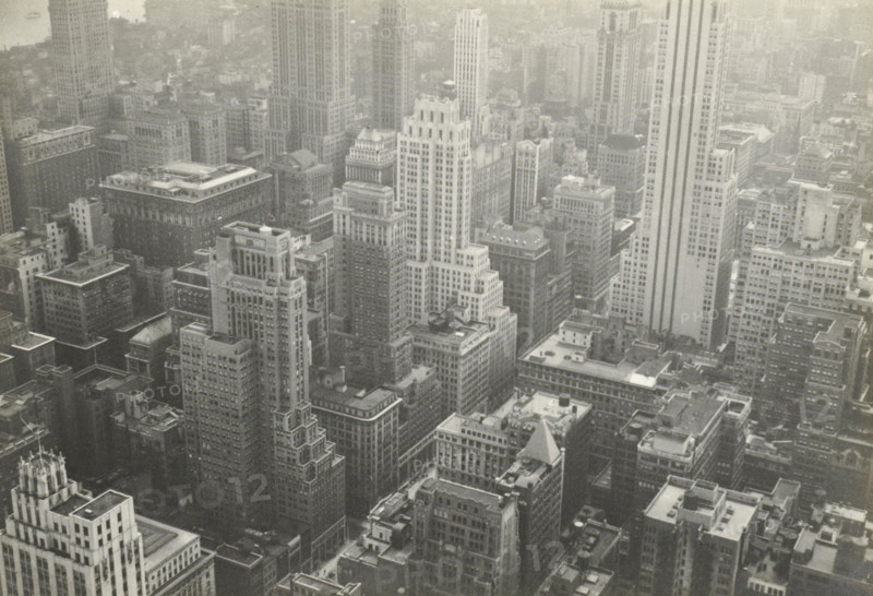 New York from RCA building, New York seen from the RCA Building (now GE Building), part of the Rockefeller Center, United States, photograph, title: 'NEW YORK FROM, RCA BUILDING', photographer: attributed to Wouter Cool, United States of America, 1936, North America, Attributed to, pasteboard, paper, gelatin silver print, height 157 mm x width 225 mm, height 315 mm x width 286 mm, city-view, and landscape with man-made constructions, skyscraper, Aerial view of a dense urban skyline with numerous tall rectangular buildings closely packed together, many with flat rooftops, visible mechanical structures, and varied architectural details such as setbacks, cornices, and decorative tops, rendered in a monochrome tone.
