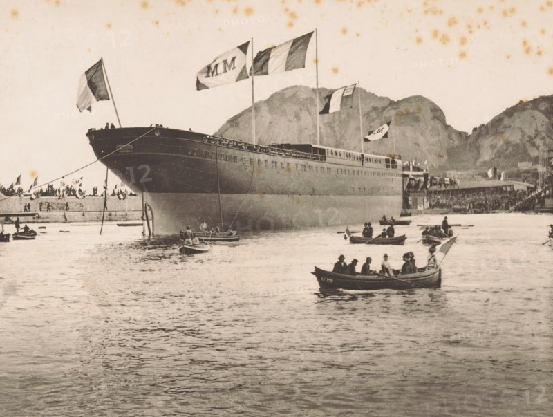 Le Polynésien à flot, Le Polynésien off the coast at La Ciotat, page, photomechanical print, inscription: '35 Boulevard des Capucines Paris', inscription: 'La Ciotat', photographer: Otto van Bosch, La Ciotat, photographer: Paul Boyer (1861-1908), cliché maker: Dujardin, printer (person): Chardon-Wittmann, c. 1888 - in or before 1890, printer (person), Provence-Alpes-Côte d'Azur, paper, photoaquatint, height 185 mm x width 231 mm, Print after page 46., harbour, ships (in general), A large ship is moored near a pier with multiple flags flying from its masts, its hull dominating the left and center of the scene and casting reflections on the water; several small rowboats with people are scattered on the water in front of the ship, and a crowd of people lines the pier along the shore; rocky hills rise in the background behind the pier and ship, and the sky above is light with scattered darker spots.