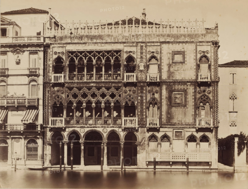 View of the Ca' d'Oro in Venice, photograph, photographer: attributed to Carlo Naya, c. 1880 - c. 1900, Attributed to, paper, pasteboard, albumen print, height 271 mm x width 356 mm, height 500 mm x width 650 mm, Venice, Ca' d'Oro, A wide stone facade with ornate gothic windows and arched loggias rises above a calm water canal, showing multiple tiers of columns and carved tracery, decorative circular motifs, carved shields, and small balconies with balustrades; adjacent palazzo sections display shuttered windows, striped awnings, and a sculpted medallion on a pale wall, while the roofline is edged with sculpted pinnacles and a tiled roof visible behind them, and wooden mooring posts stand in the water in front of the building.