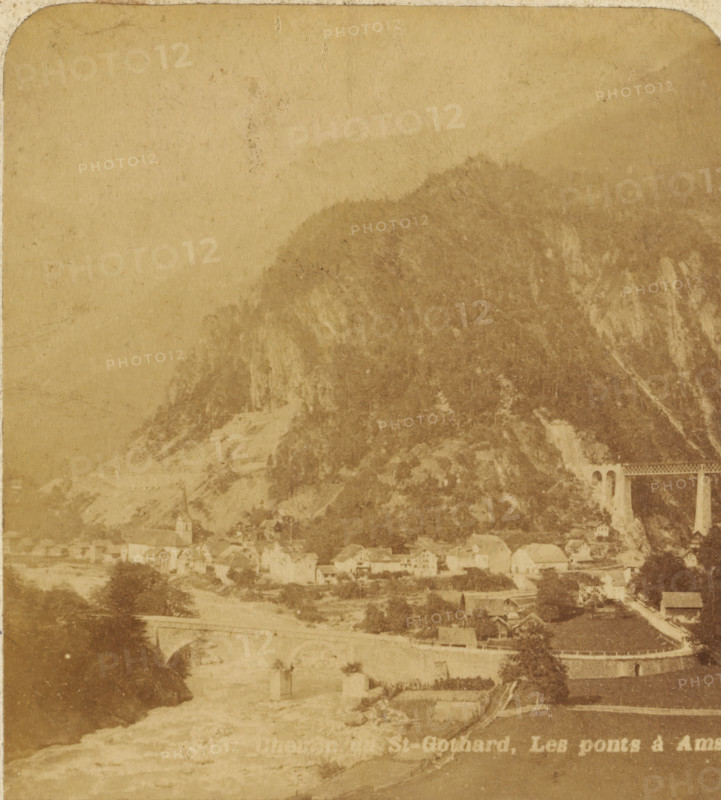 View of Amsteg with the Gotthard Massif, Switzerland, Chemin du St. Gothard : Les ponts à Amsteg, Views and landscapes in Europe, Africa and Asia, Geographical Sculpture Gallery, collected by MJ Broekhuijsen, Head of a school in Amsterdam, stereograph, Numbered 843. bottom left of photo, annotation: 'Alpine Switzerland', annotation: 'The village of AMSTEG lies at the entrance to the Madeiran Valley, 15 km north of Göschenen on the road across and the railway line through the St. Gothard., The railway line (in the background) shows a series of tunnels and viaducts here. Two viaducts are visible in the picture. The entrance to the tunnel is through, the trees hidden from view.', Uri, publisher: Merkelbach & Co., Amsterdam, compiler (person in literature): Martien Johan Broekhuijsen, c. 1905, photographer, compiler (person in literature), pasteboard, paper, albumen print, height 89 mm x width 178 mm, Part of a group of 52 stereophotos used in primary education as a supplement to school ch...