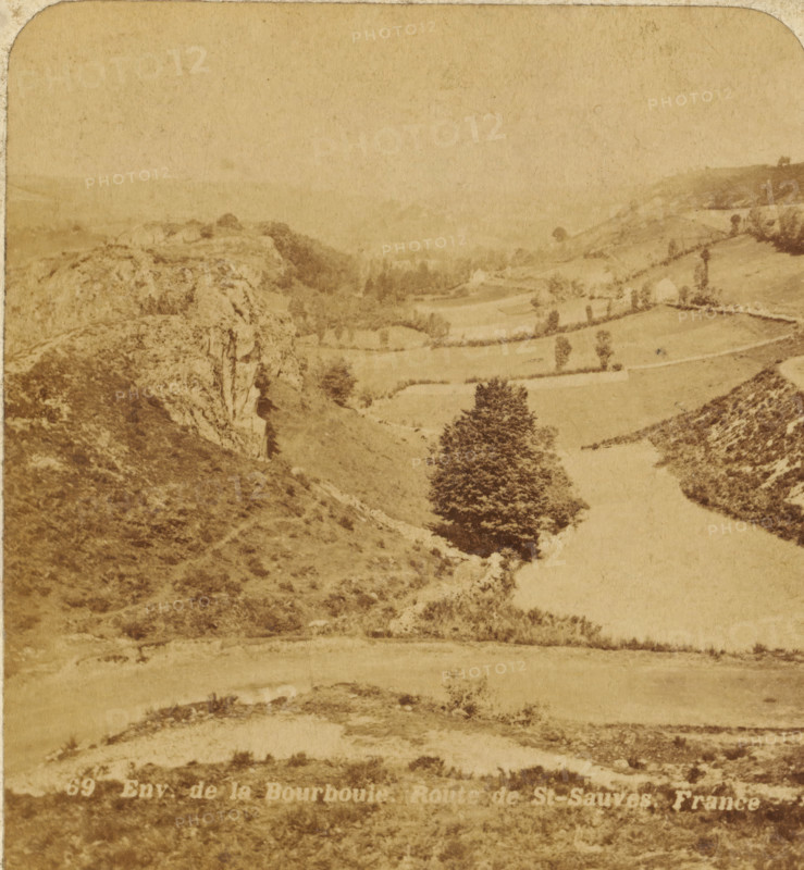 View of the cornfields between rocks in the vicinity of La Bourboule, France, Env. de la Bourboule, Route de St. Sauves. France, Views and landscapes in Europe, Africa and Asia, Geographical Sculpture Gallery, collected by MJ Broekhuijsen, Headmaster of a school in Amsterdam, stereograph, Bottom left of photo numbered: 69., annotation: 'La Bourboule and St. Sauves: seaside resorts in Auvergne, southwest of Clermont, on the Dordogne., Granite rocks on the left and right of the image. Cornfields in between.', La Bourboule, publisher: Merkelbach & Co., Amsterdam, compiler (person in literature): Martien Johan Broekhuijsen, c. 1905, photographer, compiler (person in literature), pasteboard, paper, albumen print, height 89 mm x width 178 mm, Part of a group of 52 stereophotos used in primary education as a supplement to school charts. The entire series consisted of 274 items in 10 categories (A to K)., landscapes in the temperate zone, A sepia-toned landscape photograph shows rolling hills ...