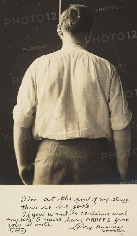 Advertisement for Kahn Bros, Louisville, picture postcard, inscription, United States of America, c. 1930 - c. 1950, photographer, North America, paper, gelatin silver print, developing gelatin silver print, height 138 mm x width 89 mm, Person, Kahn Bros, Kentucky, A sepia-toned photograph showing the back of a man from head to hips, wearing a light-colored long-sleeved shirt with sleeves rolled to the elbows and darker trousers; the man's hair is short and a rope hangs down behind his neck; the background is dark and plain, and the lower margin of the image shows a lighter area with handwritten script that is visible but not transcribed.