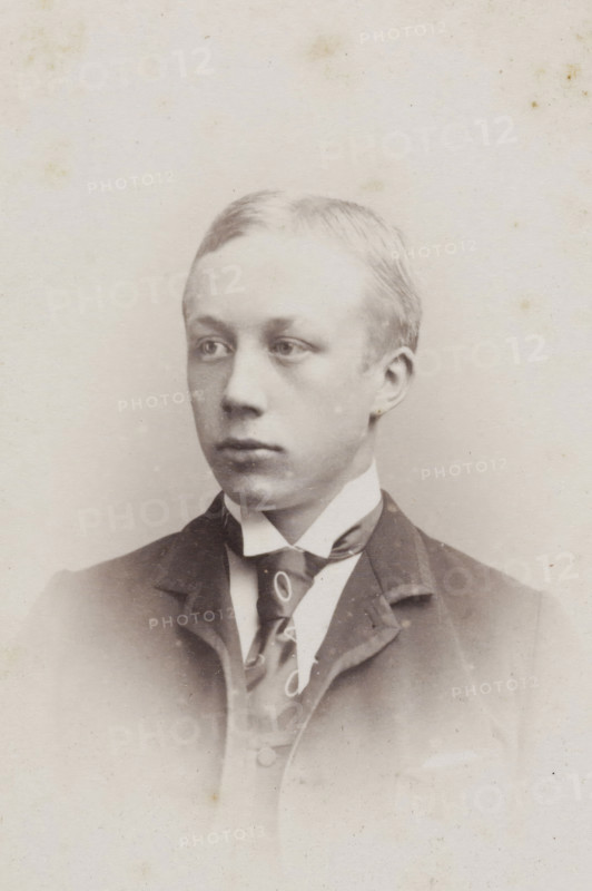 Portrait of a young man, album page, photograph, carte-de-visite, This photo is part of an album., inscription: 'JC REESINCK, ZUTPHEN, BERKELKADE B. 300., The printing plate is kept for reordering.', photographer: Johan Christiaan Reesinck, Zutphen (city), 1863 - 1900, paper, pasteboard, albumen print, height 83 mm x width 52 mm, historical persons, A head-and-shoulders portrait of a young person with short, light-colored hair, looking slightly to the side with a neutral expression, wearing a dark jacket over a high-collared shirt and a patterned necktie, shown against a plain, lightly speckled background.