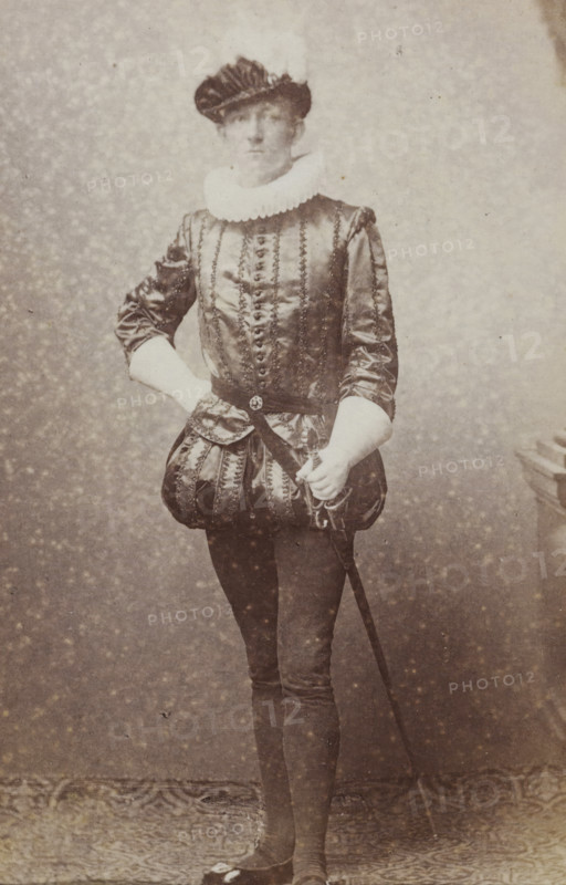 Portrait of a young man in costume with a sword, identified as CA Bergsma, album page, photograph, carte-de-visite, This photo is part of an album., name: 'CA Bergsma., 99.', inscription: 'J. Goedeljee, Photographer, HRH PRINCE ALEXANDER, of the Netherlands, PRINCE of ORANGE, and HRH, PRINCESS HENDRIK, Hoogewoerd 160, near the Plantage.', photographer: Jan Goedeljee, Leiden, 1860 - 1905, paper, pasteboard, albumen print, height 83 mm x width 52 mm, historical persons, historical costume, hacking and thrusting weapons: rapier, A sepia-toned portrait of a person standing full-length against a mottled backdrop, wearing a dark, shiny doublet with vertical decorative trim, a pleated white ruff collar, and puffed breeches; the person has a dark, pleated cap on their head, one hand resting on their hip and the other holding the hilt of a sword that extends down toward the floor, with fitted dark hose and shoes visible at the bottom.
