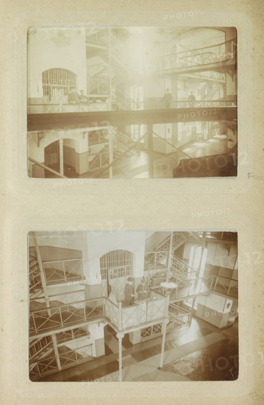 Interior of Oslebshausen prison with prison guards on a walkway, photograph, Part of Photo album of Carl Heinrich Fliegenschmidt, prison director at Oslebshausen., Oslebshausen, c. 1890 - c. 1910, photographer, Bremen (city), pasteboard, paper, daylight collodion silver print, height 78 mm x width 110 mm, prison, jail, prison personnel: jailers, warders, guards, A vertical photograph of two sepia-toned images mounted on textured paper showing an interior with multiple levels of metal walkways and staircases, arched doorways with barred openings, and column supports; the upper image is hazy and depicts railings, landings, and silhouettes of figures on a walkway, while the lower image is clearer and shows a central elevated platform with railings supported by slender columns, metal lattice staircases, window light casting shadows on a patterned floor, and a few figures standing on the platform and nearby walkways.