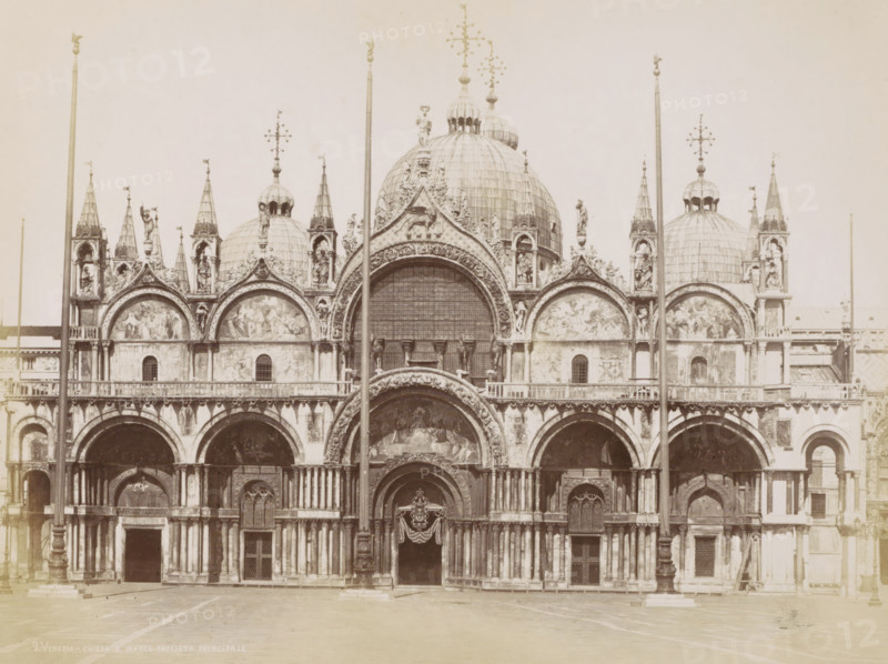 Facade of the Basilica of San Marco and domes in Venice, Venezia - chiesa S. Marco facciata principale, Eglise Saint Marc., photograph, Part of Topographical album of Venice 1881., negative number: '2', check stamp: 'Carlo Ponti Venezia', photographer: Carlo Ponti, Venice, 1860 - 1881, paper, albumen print, height 200 mm x width 260 mm, church (exterior), dome, architecture, Roman Catholic Church, travel, Basilica of San Marco, A large ornate stone facade with multiple arches and domes fills the image, featuring detailed carvings, sculpted figures, and decorative arches above doorways. Several tall slender columns and flagpoles rise in front of the building, intersecting the view of the domes and arches. The upper section shows rounded domes topped with ornamental finials and statues, and triangular gables adorned with relief panels and sculpted figures. The lower section displays arched entrances with carved surrounds, pilasters, and recessed doorways, some with decorative drapery and...