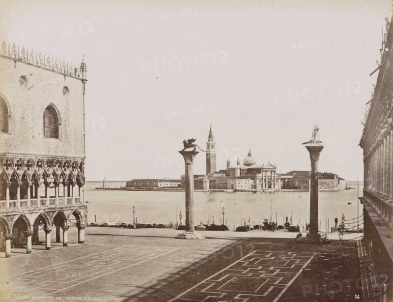 Petite Place Saint-Marc avec vue sur les Lagunes et Ile St. Georges., St. Mark's Square with two pillars and a view of Isola S. Giorgo in Venice, Venezia - Piazzetta due colonne e l'Isola S. Giorgio, photograph, Part of Topographical album of Venice 1881, check stamp: 'Carlo Ponti Venezia', negative number: '24', photographer: Carlo Ponti, Venice, 1860 - 1881, paper, albumen print, height 200 mm x width 260 mm, piece of sculpture, reproduction of a piece of sculpture, palace, square, circus, etc. (city(-scape) with figures, staffage), travel, St. Mark's Square, Isola di San Giorgio Maggiore, A wide waterfront scene shows a paved square in the foreground with geometric paving patterns and long shadows, flanked on the left by an ornate building facade with arched colonnades, circular windows, and decorative stonework, and on the right by a balustraded structure with lamps along its edge. Two tall columns rise near the water; one column is topped by a winged lion figure and the other by a...