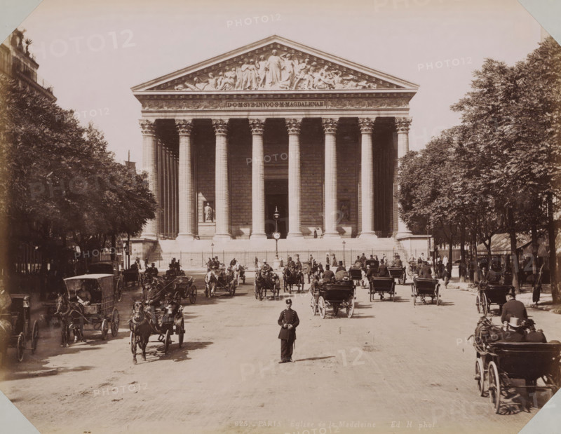 View of La Madeleine in Paris, album page, photograph, This photo is part of an album., inscription: '625. Paris. Eglise de la Madeleine. Ed. H. photot.', retailer's mark: 'E. Hautecoeur, Estampes Photographies, 35 Avenue de l'Opéra, 35, Paris', photographer: Edouard Hautecoer, Paris, 1890 - 1898, paper, albumen print, albumendruk, height 258 mm x width 355 mm, church (exterior), Madeleine, A wide neoclassical building with a triangular pediment decorated with sculpted figures sits behind a row of tall fluted columns with ornate capitals, flanked by dense rows of trees on both sides; a broad stone staircase and a low fence run across the building’s base where niches contain statues, and a lamppost stands centered in front of the entrance; a street in the foreground shows numerous horse-drawn carriages and riders moving toward and away from the building, with a uniformed policeman standing in the middle of the road and people walking along the sidewalks beneath the trees.
