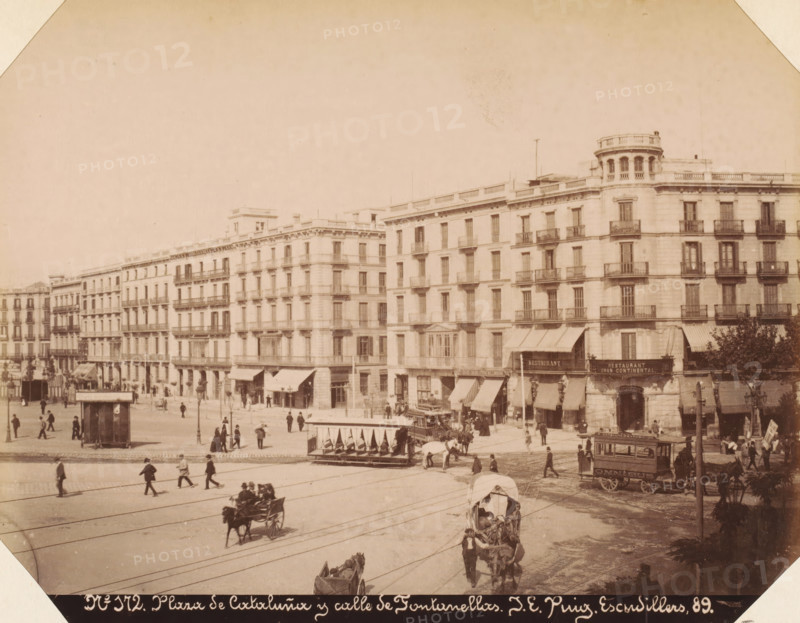 Plaza de Cataluña y calle de Fontanellas, View of Plaça de Catalunya in Barcelona, album page, photograph, This photo is part of an album., number: '172', annotation: 'Barcelona - Plaza de Cataluña', photographer: JE Puig, c. 1885 - in or before 1892-04-09, paper, albumen print, height 161 mm x width 214 mm, street, square, circus, Catalonia, Barcelona (city), A wide street scene with a row of multi-story stone buildings with balconies and awnings along the ground floor, people walking and standing on the sidewalks and in the open plaza, horse-drawn carriages and an open-sided tram or trolley stopped at the curb, a covered carriage in the foreground pulled by a horse, a small kiosk or booth near the plaza, several lampposts and trees at the street edge, and tram tracks running across the paved road.