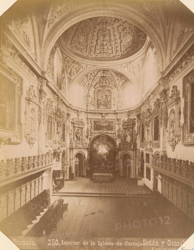 Interior of Real Monasterio de La Cartuja in Granada, Granada - Interior de la Iglesia de Cartuja, album page, photograph, This photo is part of an album., annotation: 'Granada - Cartuja', number: '250.', photographer: Señan y Gonzalez, c. 1885 - c. 1892-03-12, paper, albumen print, height 206 mm x width 161 mm, interior of church, Andalusia, Granada, A wide interior view of an ornate church nave with a high decorated dome and vaulted ceiling featuring intricate carved and painted panels, flanked by elaborately framed paintings and sculptural reliefs along both side walls, a central ornate altar area with decorative archways and religious imagery, rows of wooden pews on the left, carved balconies and balustrades lining the sides, patterned floor tiles leading toward the altar, and soft sepia-toned lighting across the architectural details.