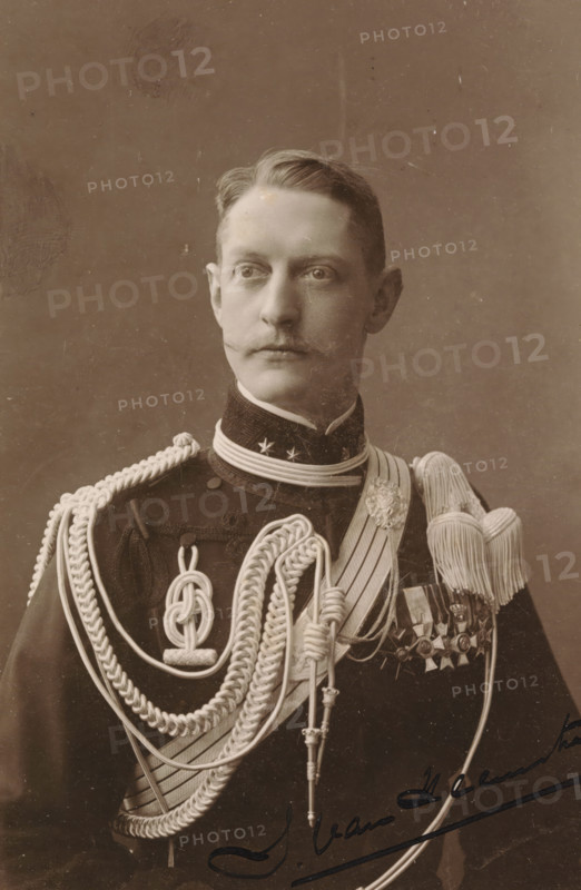 Toto van Heemstra, Portrait of Toto van Heemstra, photograph, cabinet photograph, signature: 'Toto van Heemstra', signature: 'Ebner, The Hague, Amsterdam', photographer: Ferdinand Robert Ebner, Amsterdam, 1880 - 1920, pasteboard, paper, matte daylight collodion silver print, height 145 mm x width 93 mm, height 165 mm x width 103 mm, Person, historical persons, Netherlands, A sepia portrait of a man shown from the chest up wearing a dark military uniform adorned with elaborate braided cords and aiguillettes draped across his chest, a high collar with decorative stars, a sash, a row of medals on his left side, and large tasseled epaulettes; he has neatly combed hair, a trimmed mustache, a neutral expression, and is gazing slightly to his left against a plain backdrop.