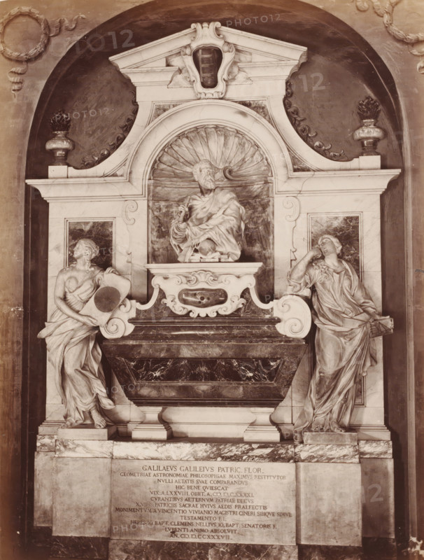 Sepulchral monument to Galileo Galilei in the Santa Croce in Florence, Italy, Tomba di Galileo S. Croce, Firenze, photograph, address: 'GIACOMO BROGI, FOTOGRAFO-EDITORE, FIRENZE, LUNG ARNO DELLE GRAZIE 15', number: '3136.', photographer: Giacomo Brogi, Florence, publisher: Edizioni Brogi, after sculpture by various manufacturers, 1864 - 1881, various manufacturers, after sculpture by, Tuscany, pasteboard, paper, albumen print, height 471 mm x width 350 mm, Person, Galileo Galilei, piece of sculpture, reproduction of a piece of sculpture, grave-building, monumental tomb, Santa Croce, A sculpted stone monument set into a recessed arched niche features a central marble sarcophagus with a richly veined dark front and ornate carved white supports, surmounted by a semicircular shell niche containing a seated bearded male figure draped in flowing robes holding an object near his chest, flanked on either side by two standing female figures in classical drapery each posed on pedestals with one ...