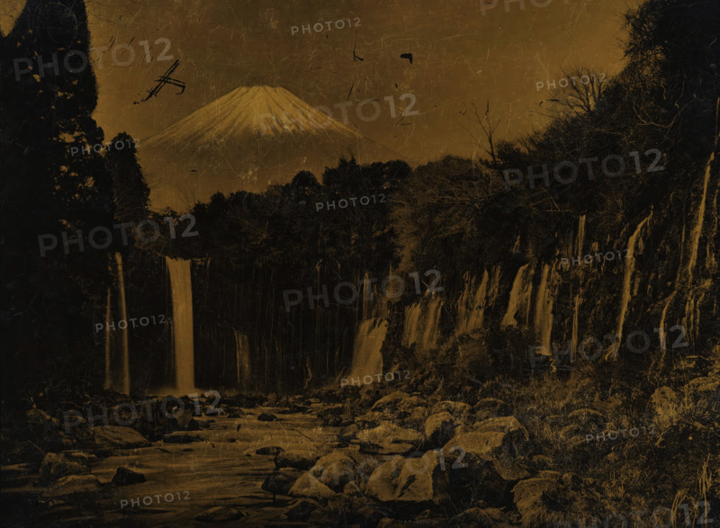 View of Mount Fuji with waterfalls, photograph, Japan, printer (person): attributed to Hanbeh Mizuno, Yokohama, 1890 - 1920, photographer, printer (person), Kanagawa, Honshu, Attributed to, plant material, biological material, inorganic material, wood (plant material), metal, lacquer photo, photography on Japanese lacquerware, height 110 mm x width 145 mm, waterfall, mountains, Fuji, A landscape dominated by a large, snow-capped mountain in the background with a conical peak; in front of it a dense dark treeline stretches across the scene, flanked by tall, shadowed trees on either side; several narrow waterfalls descend from a rocky cliff into a river below, with water flowing past scattered boulders in the foreground; the sky and entire image have a textured, scratched surface and a sepia-toned appearance.