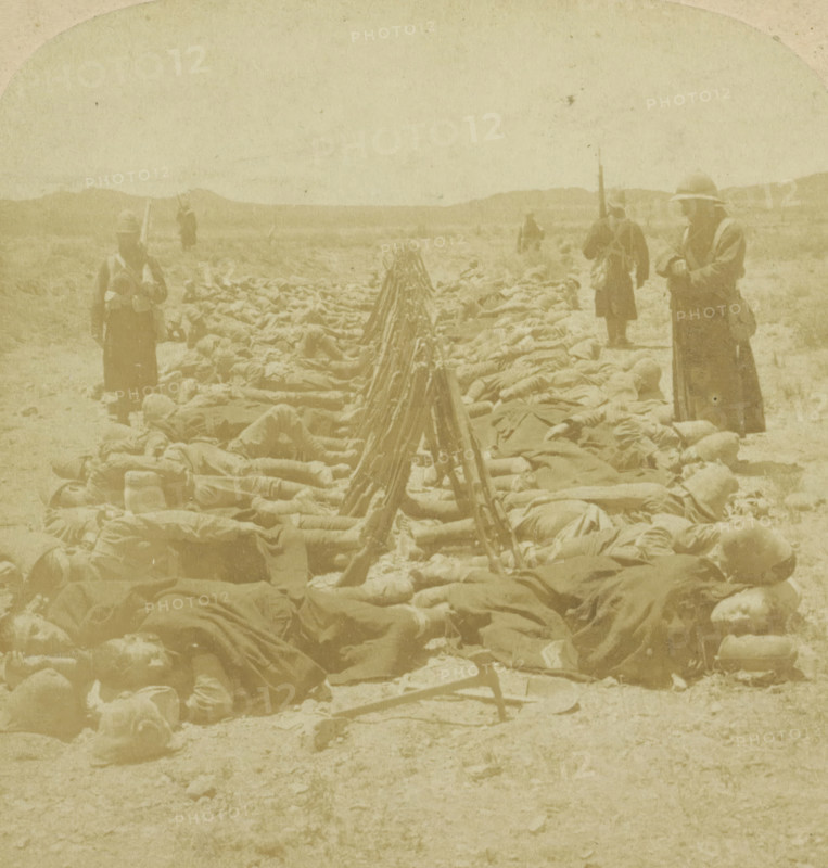 British soldiers sleeping next to their guns near Colesberg, South Africa, 'When the Cannon's roar is still'-sleeping by their Arms (Dec. 30th) before Colesberg, stereograph, copyright notice: 'Copyright 1900 by Underwood & Underwood.', inscription: 'SUN SCULPTURE, UU, TRADEMARK, Works and Studios, Arlington, NJ Westwood, NJ Washington, DC', inscription: ''When the Cannon's roar is still'-sleeping by their Arms (Dec. 30th) before Colesberg, South Africa.', Colesberg, publisher: Underwood and Underwood, New York (city) (possibly), 1900, photographer, North America, pasteboard, paper, albumen print, height 88 mm x width 178 mm, the soldier, the soldier's life, Second Boer War (1899-1902), A sepia-toned scene shows a wide flat landscape with low hills in the distance and a sky taking up the upper portion of the image, a long row of rifles propped muzzle-up forming a central line that recedes toward the horizon, flanked on both sides by numerous figures lying on the ground covered with bla...