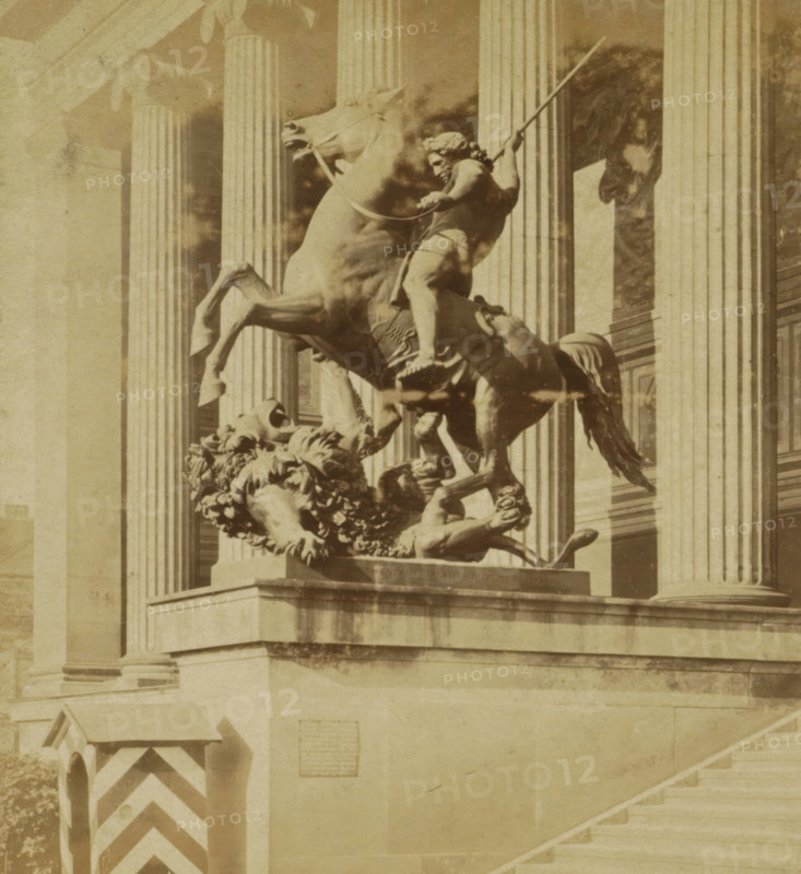 Statue of the Lion Killer after Albert Wolff for the Altes Museum in Berlin, Lowentödter von Wolff for the Königlichen Museum, Berlin and Environment, stereograph, number: '40.', photographer: Sophus Williams, Berlin, after sculpture by Albert Wolff, 1876, Albert Wolff, after sculpture by, pasteboard, paper, albumen print, albumendruk, height 86 mm x width 176 mm, monument, statue, front steps, Altes Museum, A sepia-toned photograph of a stone equestrian statue showing a rearing horse and a partially draped rider holding a long staff, positioned on a raised plinth in front of tall fluted columns; below the horse a sculpted lion lies on its back with a mane of carved curls, and decorative foliage forms part of the base; to the left a small guardhouse with diagonal stripes stands near the corner of the plinth, and a broad flight of stone steps ascends to the right.