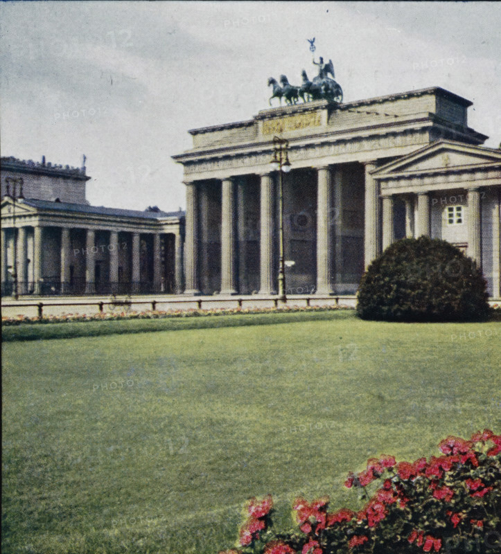 Brandenburg Gate in Berlin, Brandenburger Tor., Porte de Brandenburg., Arch of Brandenburg., Porta di Brandeburgo., Puerta de Brandemburgo, Berlin., Berlino, photomechanical print, stereograph, inscription: 'Warenzeichen, No. 142123', inscription: 'Series 7 Berlin I No. 55-60', inscription: 'DRGM, No. 437756', inscription: '4.', inscription: 'Westablschluss der Hauptstrasse 'Unter den, ', inscription: 'Chromoplast-Bild, No. 55', Berlin, cliché maker: Farbenphotographischen Gesellschaft, Stuttgart, publisher: Farbenphotographischen Gesellschaft, 1911 - 1919, Farbenphotographischen Gesellschaft, photographer, cliché maker, publisher, Baden-Württemberg, paper, pasteboard, three-color autotype, height 90 mm x width 180 mm, city gate, Brandenburg Gate, A classical stone building with tall columns and a triangular pediment is visible behind a large manicured lawn, with a sculptural group atop the roof showing figures and horses, a lamp post standing near the front of the columns, a rounded s...
