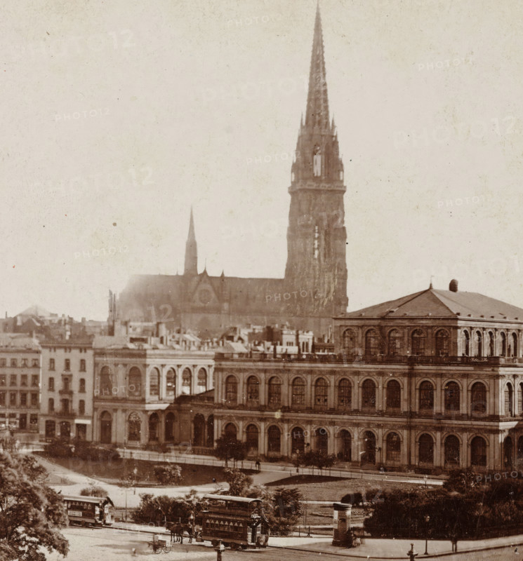 Hamburg, Rathhausmarkt, View of Hamburg with the Stock Exchange in the foreground and the Nikolaiturm behind it, stereograph, 1873 - 1890, photographer, paper, pasteboard, daylight collodion silver print, height 88 mm x width 179 mm, city-view in general, 'veduta', parts of church exterior and annexes: tower, Exchange, Bourse, Nikolaiturm, A sepia-toned cityscape showing a large ornate building with rows of arched windows and a pitched roof in the foreground, a tall cathedral spire rising behind it along with a smaller spire, a riverside promenade and tree-lined green space in front of the buildings, horse-drawn double-decker trams and a horse-drawn carriage on the street, a cylindrical kiosk near the curb, and scattered pedestrians and street furniture visible along the sidewalks.